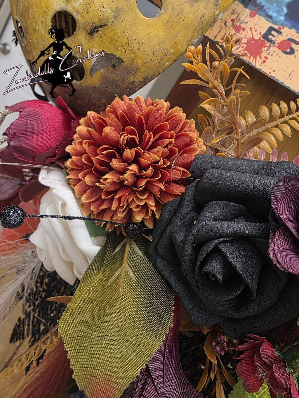 Close-up of a decorative headband with flowers and feathers, featuring a brand logo.