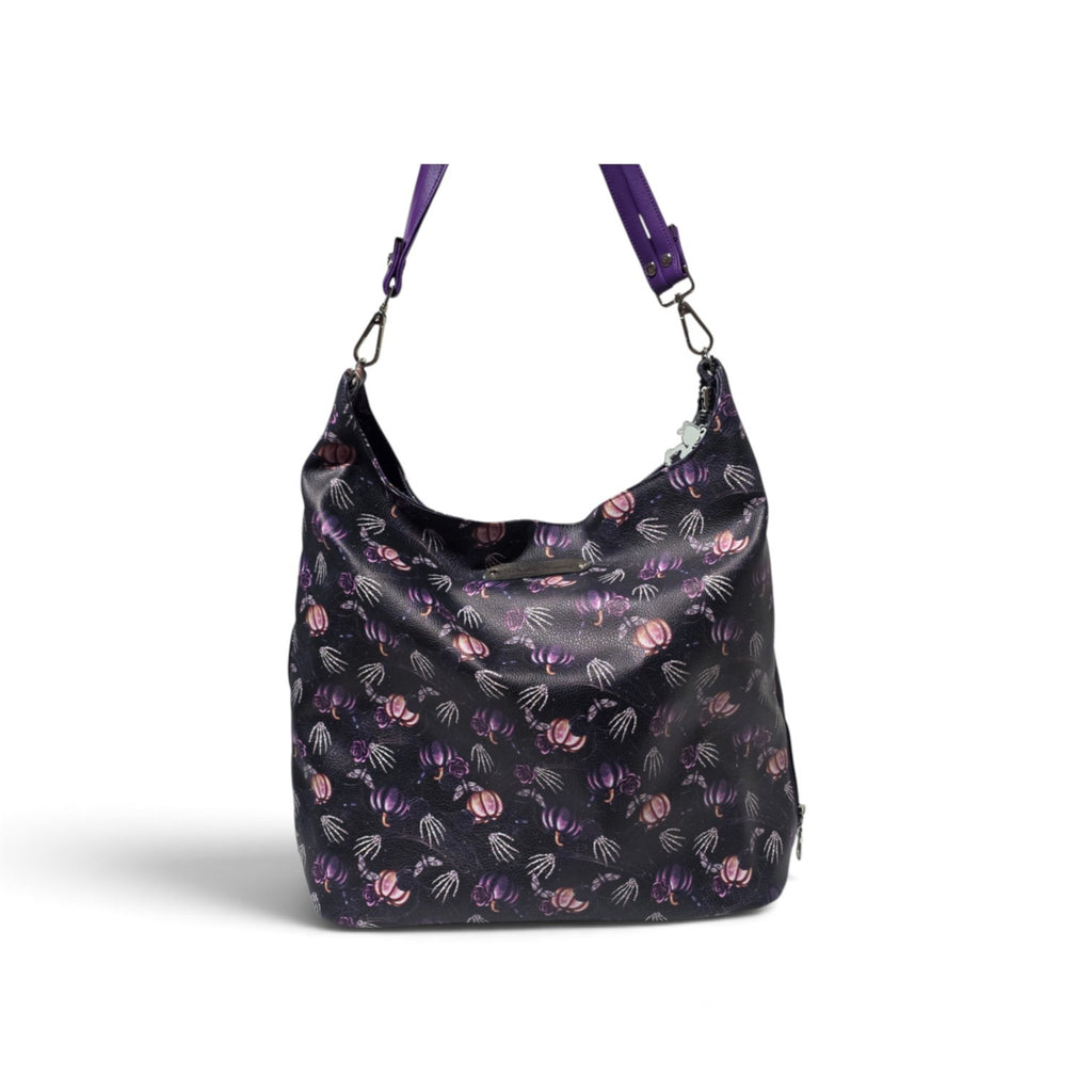 A black hobo shoulder bag with a purple and Skeleton pumpkin pattern, featuring a matching purple strap and silver-tone hardware, shown against a plain white background.