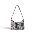 A black and white patterned hobo shoulder bag with a long strap, featuring a collage of vintage-style portrait frames and monochrome illustrations on a clean white background.