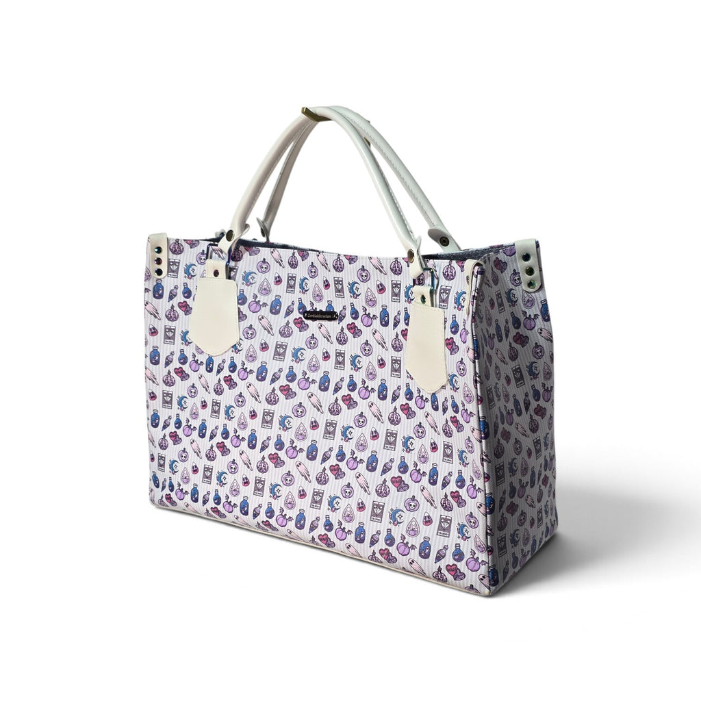A tote bag with a light purple and white patterned body featuring small illustrated icons, cream-colored handles, and cream hanging tags, shown on a white background.