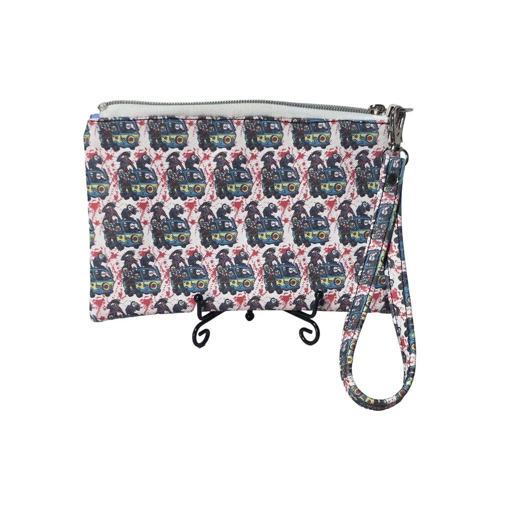 A zippered wristlet clutch with an all-over repeating pattern of black and blue fire trucks on a white background, featuring a matching wrist strap and displayed on a small black stand.