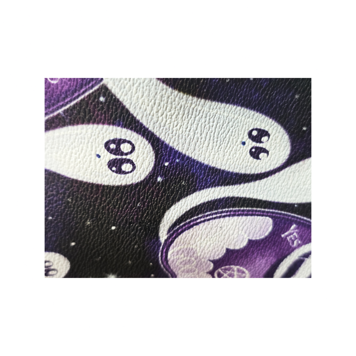 A close-up of a textured material featuring a cute cartoon ghost pattern on a dark purple and black starry background.