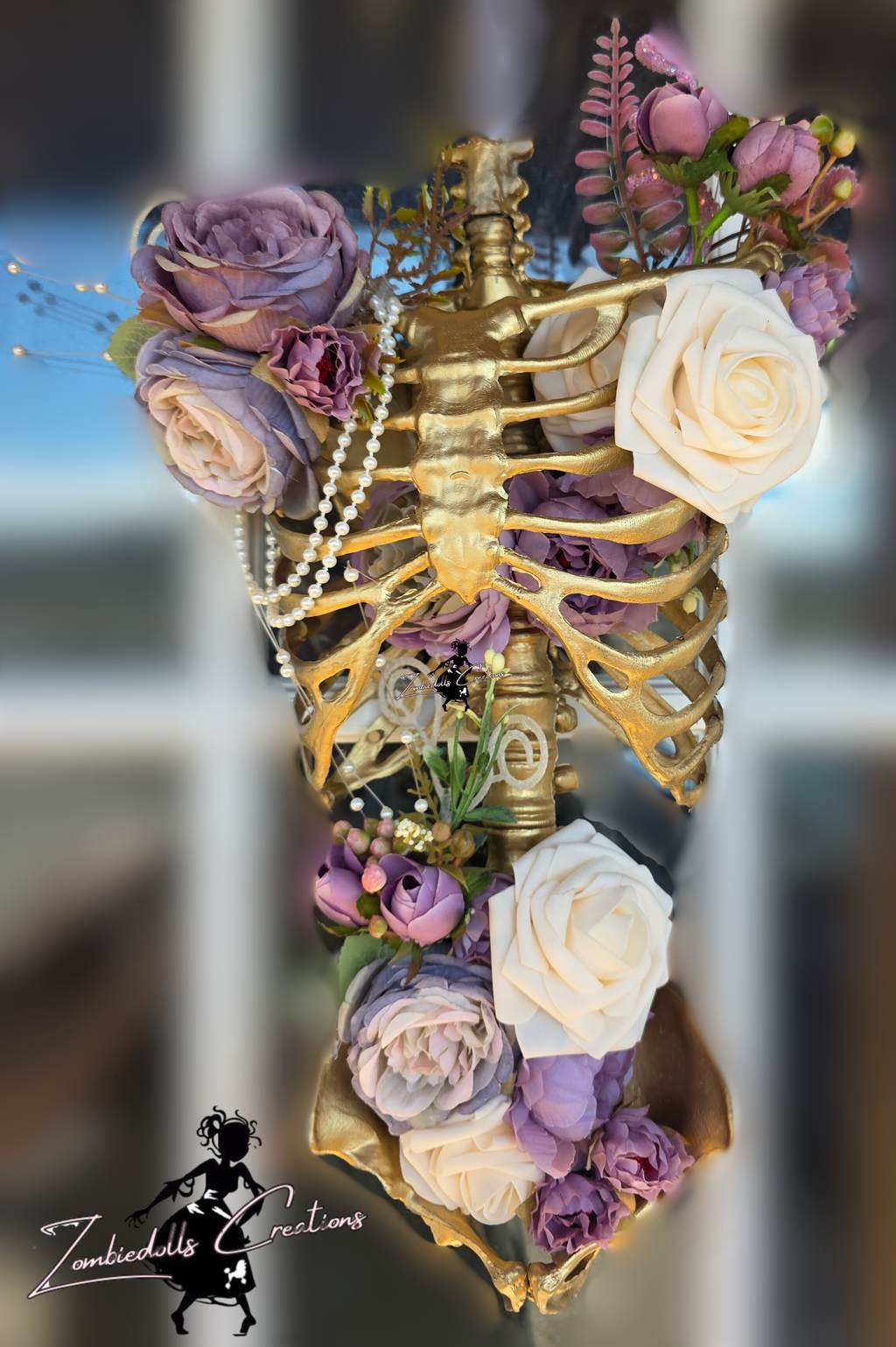 Gold skeleton with flowers and jewelry against a blurred background