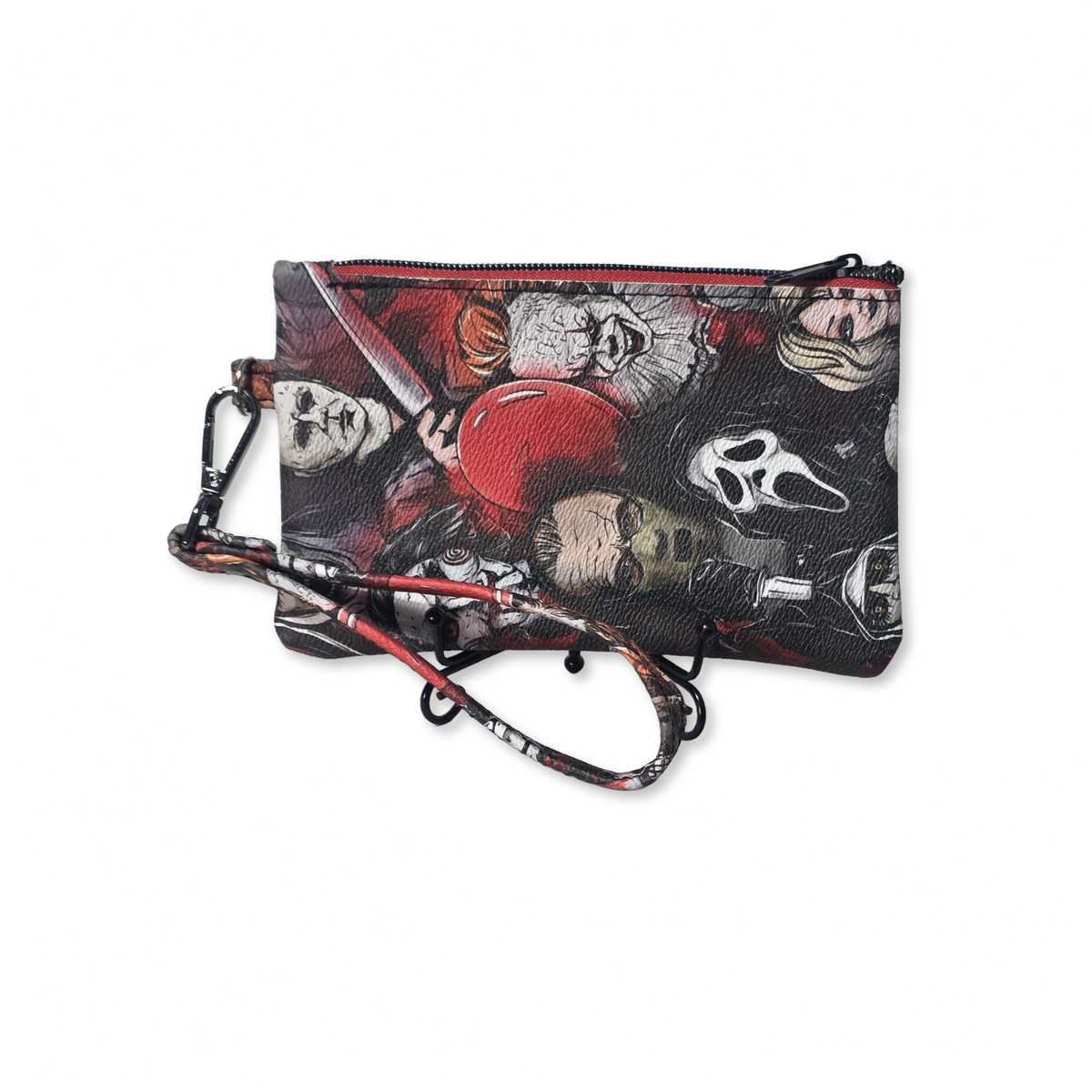 A small zip pouch with a wrist strap, featuring a horror movie character print including Ghostface, Harley Quinn, and a red baseball, on a plain white background.