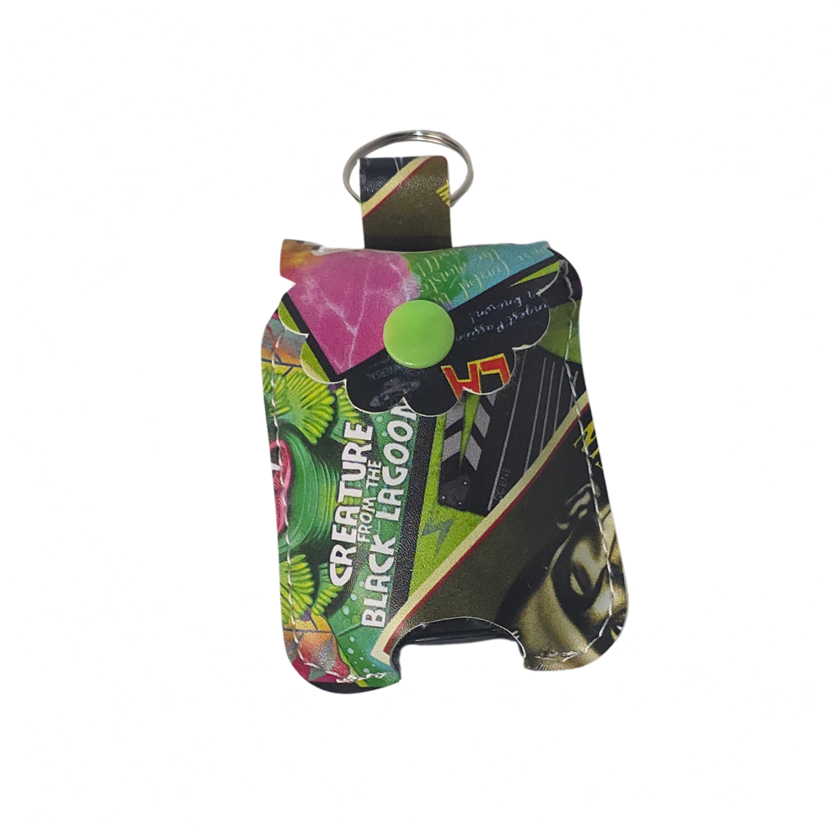 A small rectangular keychain-style pouch with a metal key ring and a bright green snap button, featuring a colorful collage print with green foliage, black and white graphic elements, and the text 'CREATURE OF THE BLACK LAGOON'.