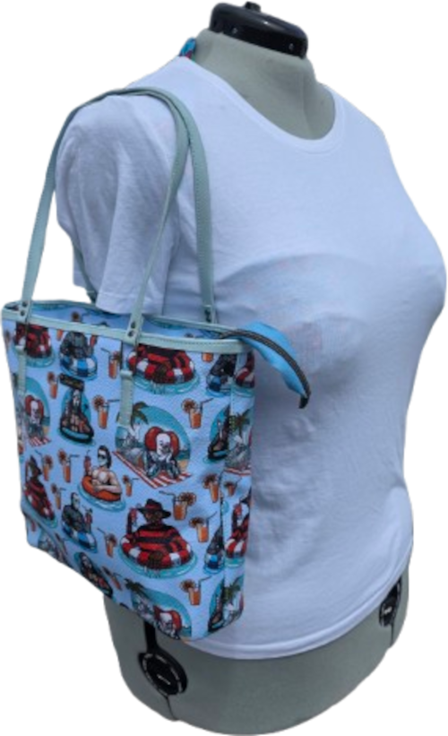 A tote bag with a light blue background and a colorful cartoon print, displayed on a gray mannequin wearing a white t-shirt against a white background.
